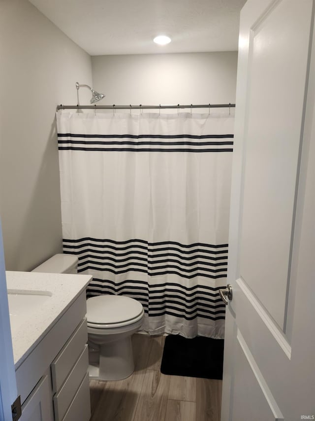 full bath featuring toilet, a shower with shower curtain, vanity, and wood finished floors