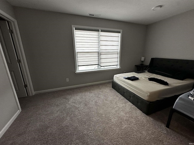 carpeted bedroom with visible vents, baseboards, and a textured ceiling