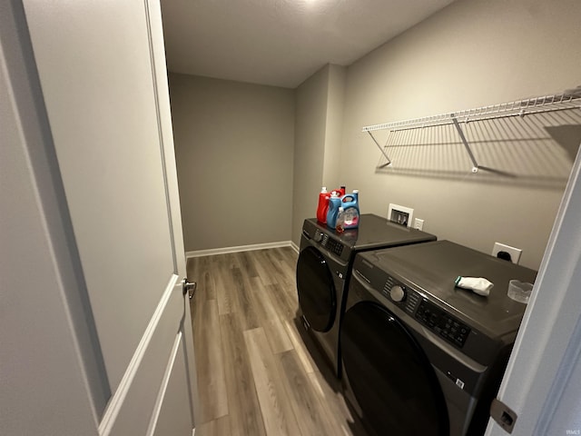 washroom featuring independent washer and dryer, laundry area, wood finished floors, and baseboards