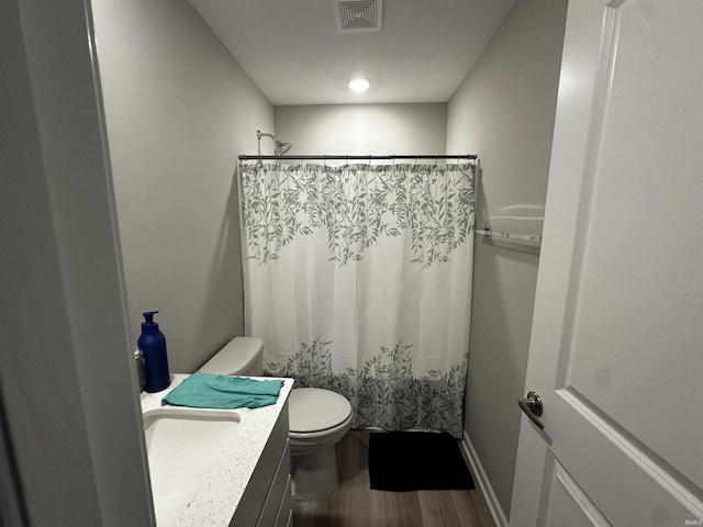 bathroom featuring vanity, a shower with curtain, toilet, visible vents, and wood finished floors