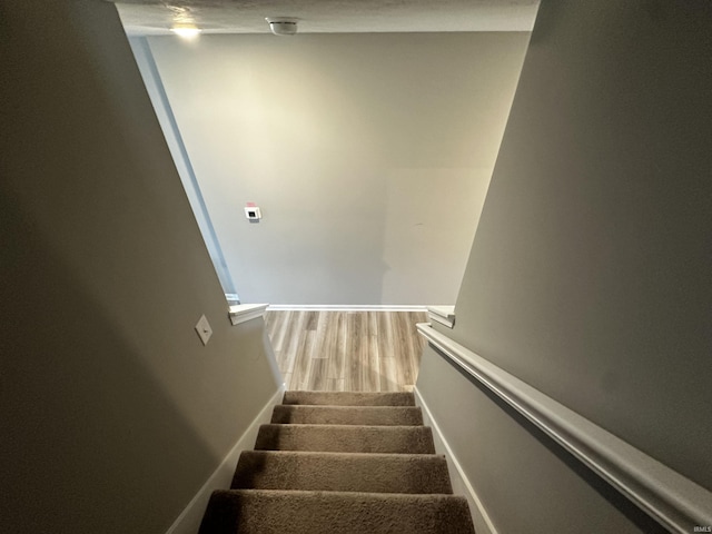 staircase featuring baseboards and wood finished floors