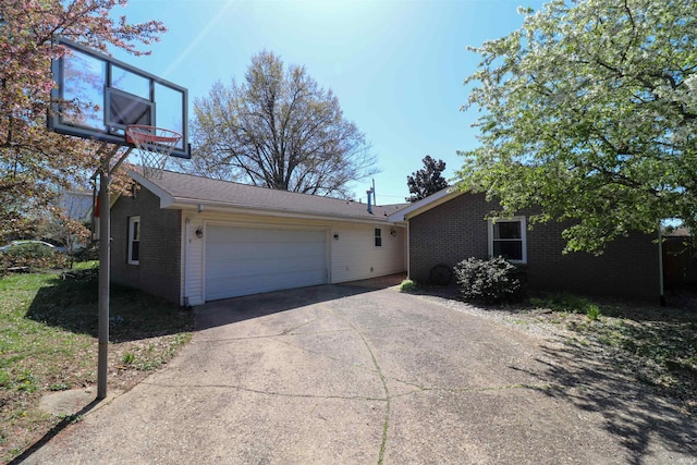 view of property exterior with a garage, brick siding, and driveway