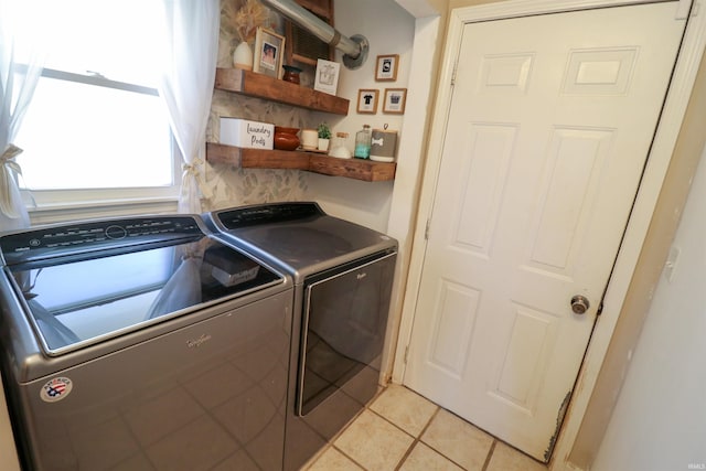 clothes washing area featuring laundry area, separate washer and dryer, and light tile patterned flooring