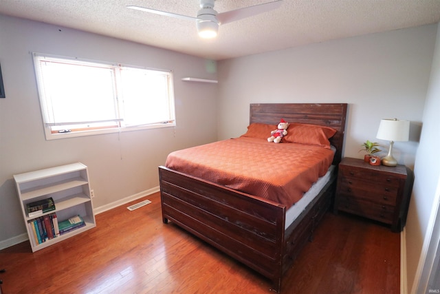 bedroom featuring a textured ceiling, wood finished floors, baseboards, and visible vents