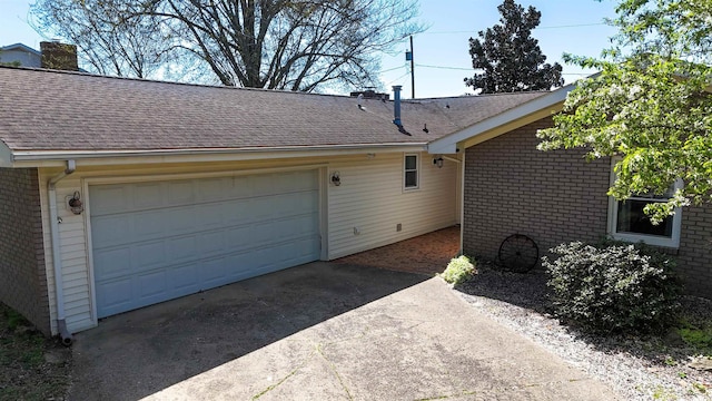 view of home's exterior with concrete driveway, roof with shingles, a chimney, an attached garage, and brick siding