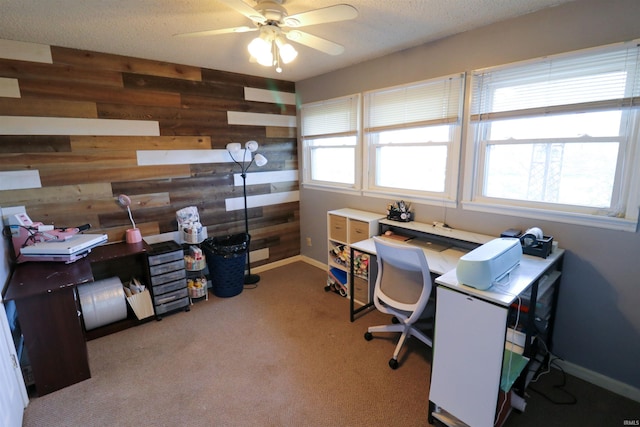 home office featuring wood walls, ceiling fan, plenty of natural light, and carpet flooring