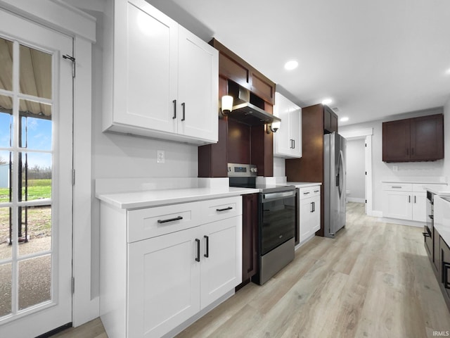 5307 Millersburg Rd, Evansville, IN 47725 - kitchen with wall chimney range hood, recessed lighting, light wood-style flooring, light countertops, and stainless steel appliances