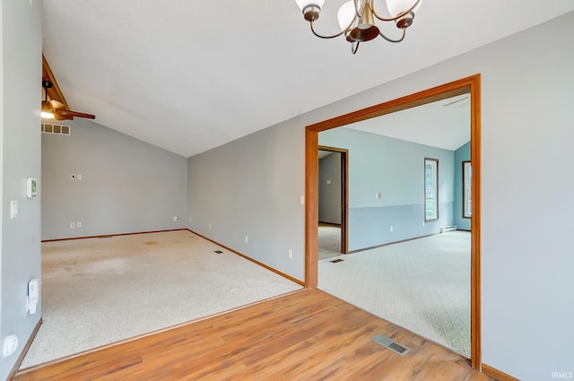 empty room featuring visible vents, baseboards, wood finished floors, and lofted ceiling
