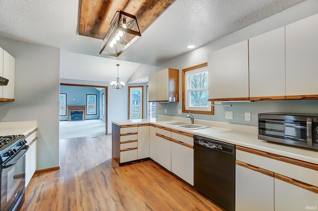 kitchen with light wood-style flooring, black appliances, a chandelier, a sink, and light countertops