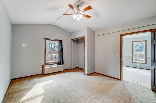unfurnished bedroom with visible vents, an AC wall unit, light carpet, and baseboards