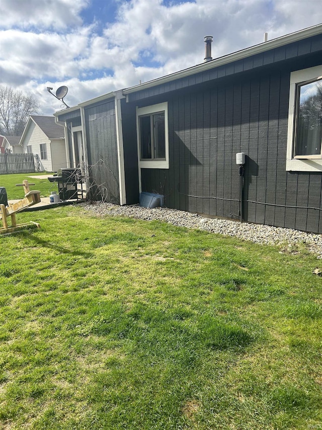 view of side of property with a lawn and fence
