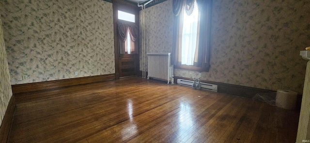 126 E 4th St, Mount Carmel, IL 62863 - spare room featuring a baseboard radiator, wallpapered walls, radiator, and wood-type flooring