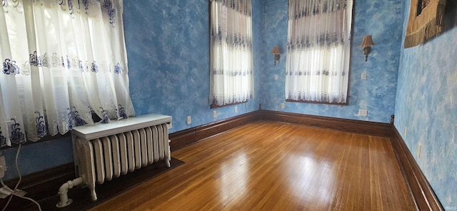 126 E 4th St, Mount Carmel, IL 62863 - empty room featuring wallpapered walls, radiator heating unit, wood-type flooring, and baseboards