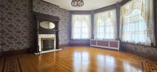 126 E 4th St, Mount Carmel, IL 62863 - unfurnished living room featuring a large fireplace, baseboards, radiator, and wallpapered walls