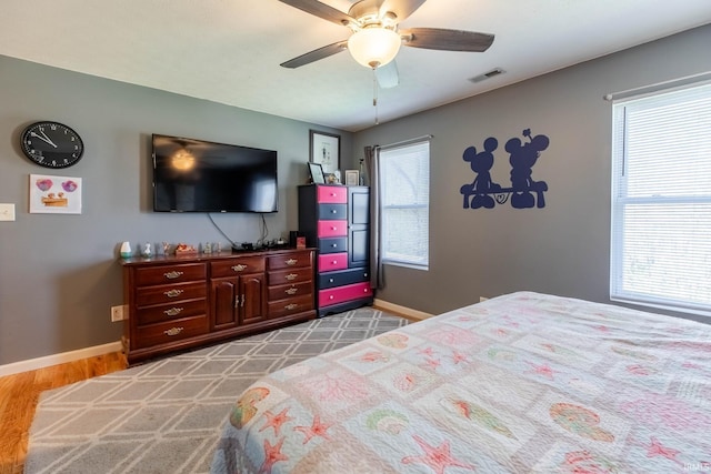 bedroom with wood finished floors, ceiling fan, baseboards, and visible vents