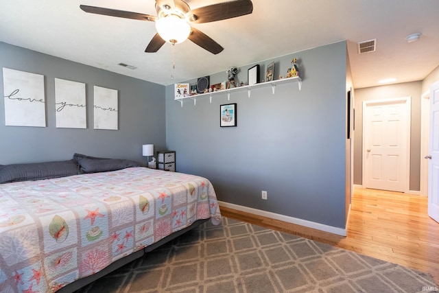 bedroom with ceiling fan, visible vents, baseboards, and wood finished floors