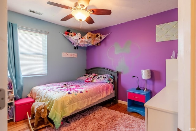 bedroom featuring wood finished floors, ceiling fan, baseboards, and visible vents