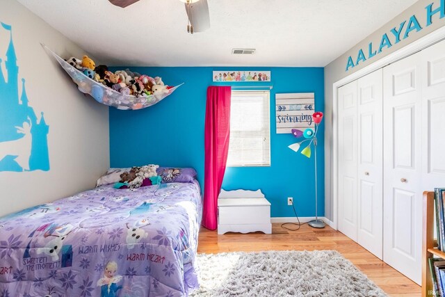 bedroom featuring visible vents, a closet, baseboards, ceiling fan, and wood finished floors