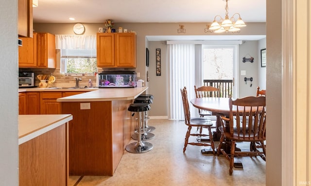kitchen featuring tasteful backsplash, light countertops, a kitchen bar, pendant lighting, and a sink