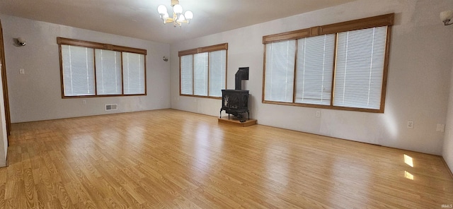 402 Easy St, Mount Carmel, IL 62863 - unfurnished living room with visible vents, a wood stove, an inviting chandelier, and light wood-style floors