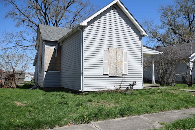 view of home's exterior with a lawn and roof with shingles