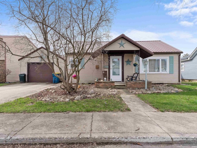 bungalow-style house with a garage, metal roof, and driveway