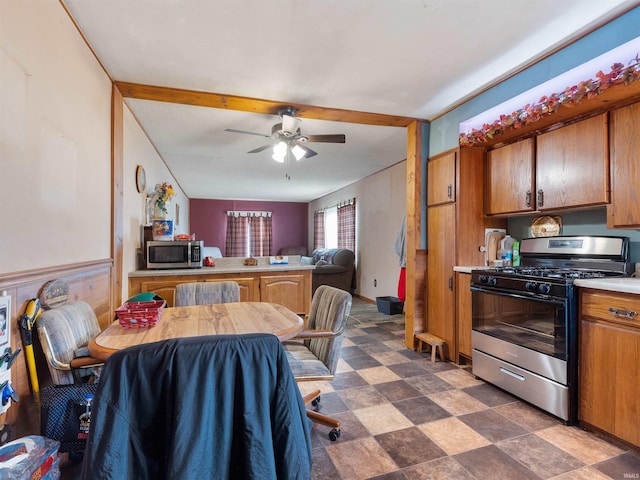 interior space with ceiling fan, a peninsula, light countertops, stainless steel appliances, and brown cabinets