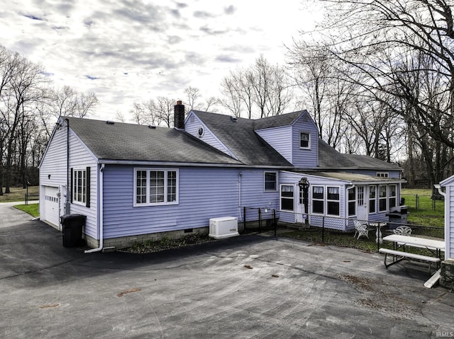 411 S County Road 550 E, Selma, IN 47383 - rear view of house featuring a shingled roof, a sunroom, a garage, a chimney, and a patio