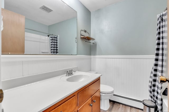 bathroom featuring visible vents, a wainscoted wall, a baseboard heating unit, and wood finished floors