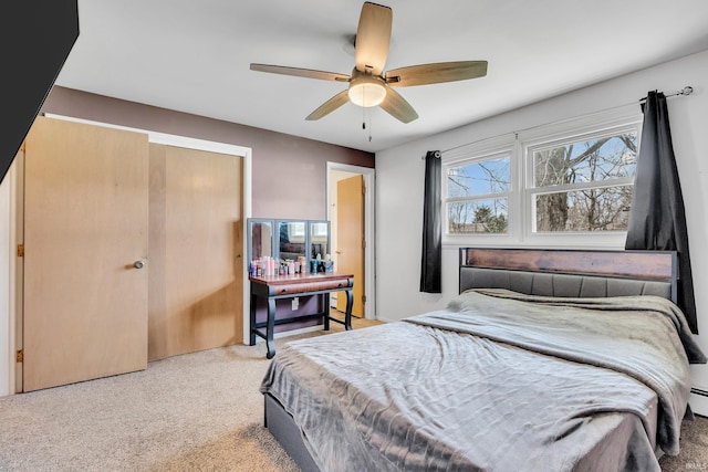 carpeted bedroom featuring baseboard heating, a closet, and a ceiling fan