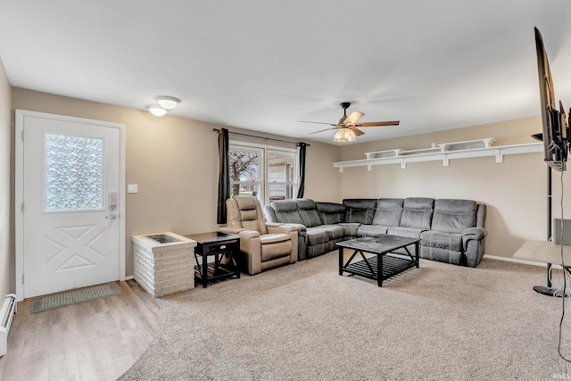 living area with baseboard heating, wood finished floors, ceiling fan, and baseboards