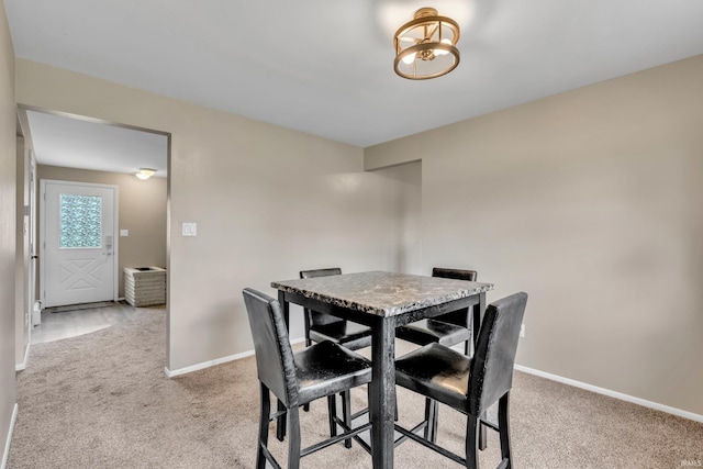 dining area featuring light carpet and baseboards