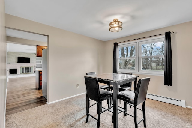dining room featuring a baseboard radiator, carpet flooring, baseboards, and a fireplace