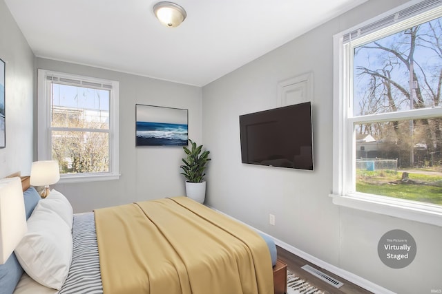 bedroom with wood finished floors, baseboards, and visible vents