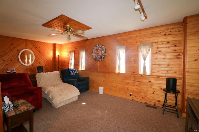 carpeted living room featuring track lighting, a ceiling fan, and visible vents