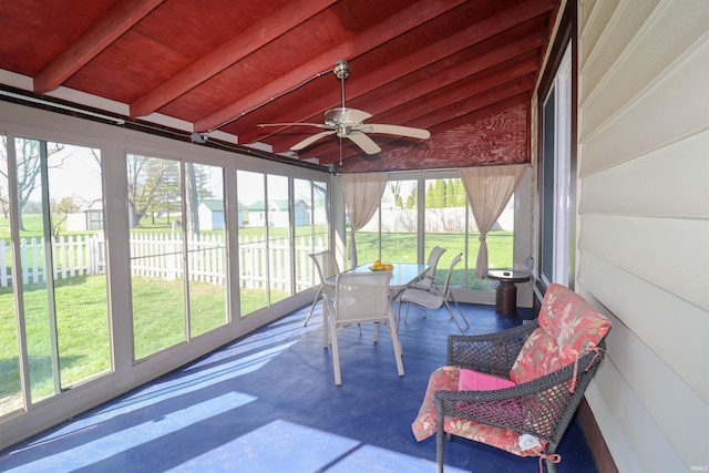 sunroom featuring beamed ceiling, a ceiling fan, and a wealth of natural light