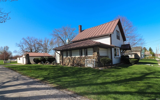 view of home's exterior featuring a standing seam roof, a yard, metal roof, stone siding, and a chimney