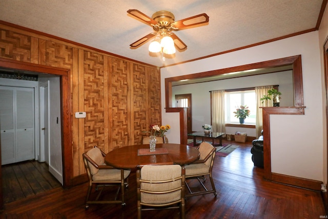 dining room with baseboards, a textured ceiling, crown molding, hardwood / wood-style floors, and ceiling fan