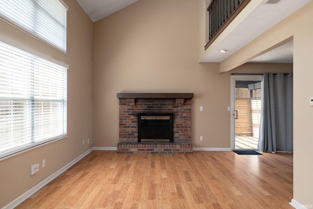 526 Cambridge Dr, Kokomo, IN 46902 - unfurnished living room with a towering ceiling, light wood-type flooring, baseboards, and a brick fireplace