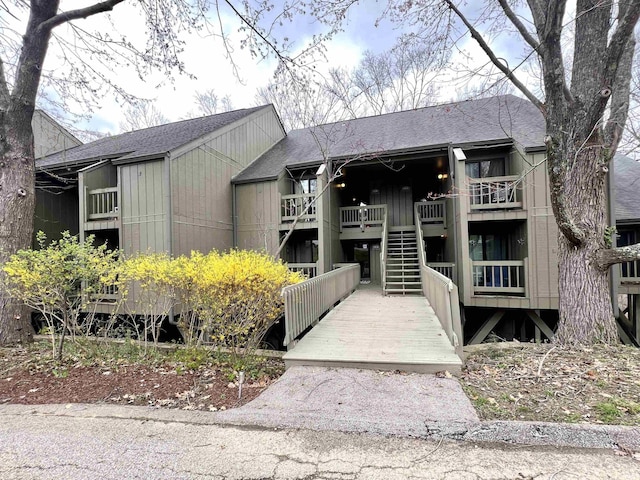 view of front of property featuring a shingled roof and stairway