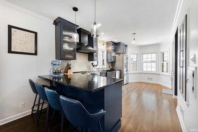 4707 Old Mill Rd, Fort Wayne, IN 46807 - kitchen featuring tasteful backsplash, ornamental molding, wall chimney range hood, light wood-style flooring, and visible vents