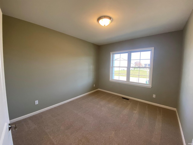 carpeted spare room featuring visible vents and baseboards