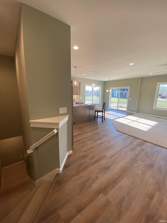 hallway with a wealth of natural light, recessed lighting, wood finished floors, and baseboards