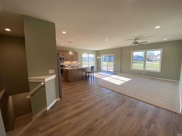 unfurnished living room featuring baseboards, recessed lighting, and dark wood-style floors