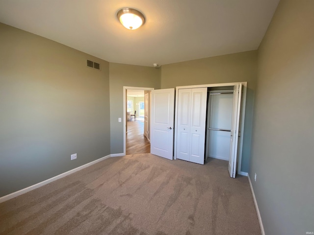 unfurnished bedroom with a closet, visible vents, baseboards, and carpet floors