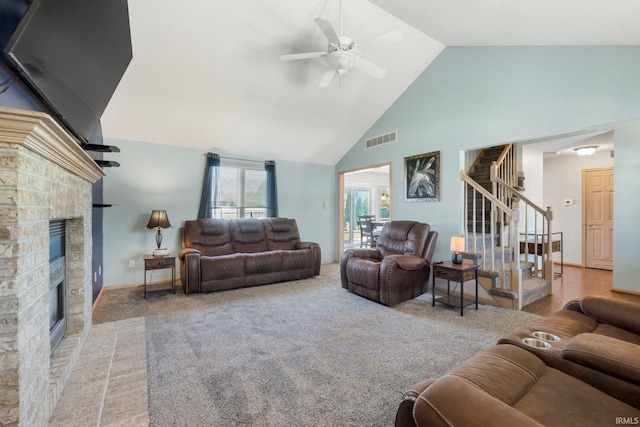 living room featuring stairs, a fireplace, visible vents, a ceiling fan, and high vaulted ceiling