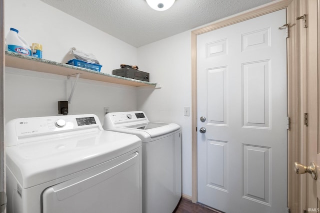clothes washing area with a textured ceiling, washer and clothes dryer, and laundry area