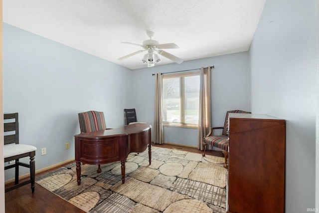 office featuring a ceiling fan, a textured ceiling, wood finished floors, and baseboards