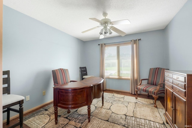 home office featuring a textured ceiling, ceiling fan, light wood-style flooring, and baseboards