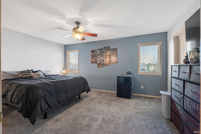 carpeted bedroom with a textured ceiling, a ceiling fan, and baseboards